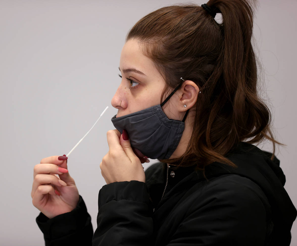 Karina Lewis of Las Vegas uses a nasal swab for a COVID-19 test on the first day of testing ope ...