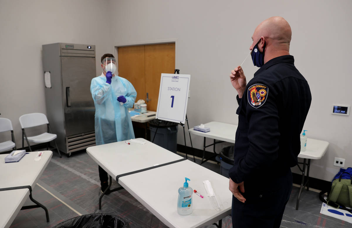 Travis Haldeman, a Clark County Fire Department engineer, uses a nasal swab for a COVID-19 test ...