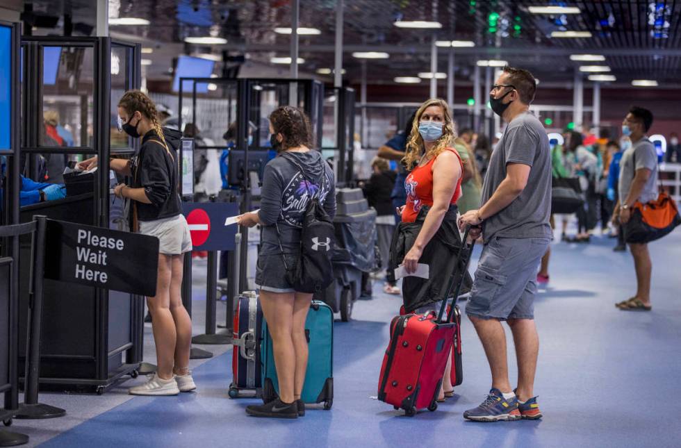 Passengers make their way through the TSA checkpoint in Terminal 1 as COVID-19 safety precautio ...