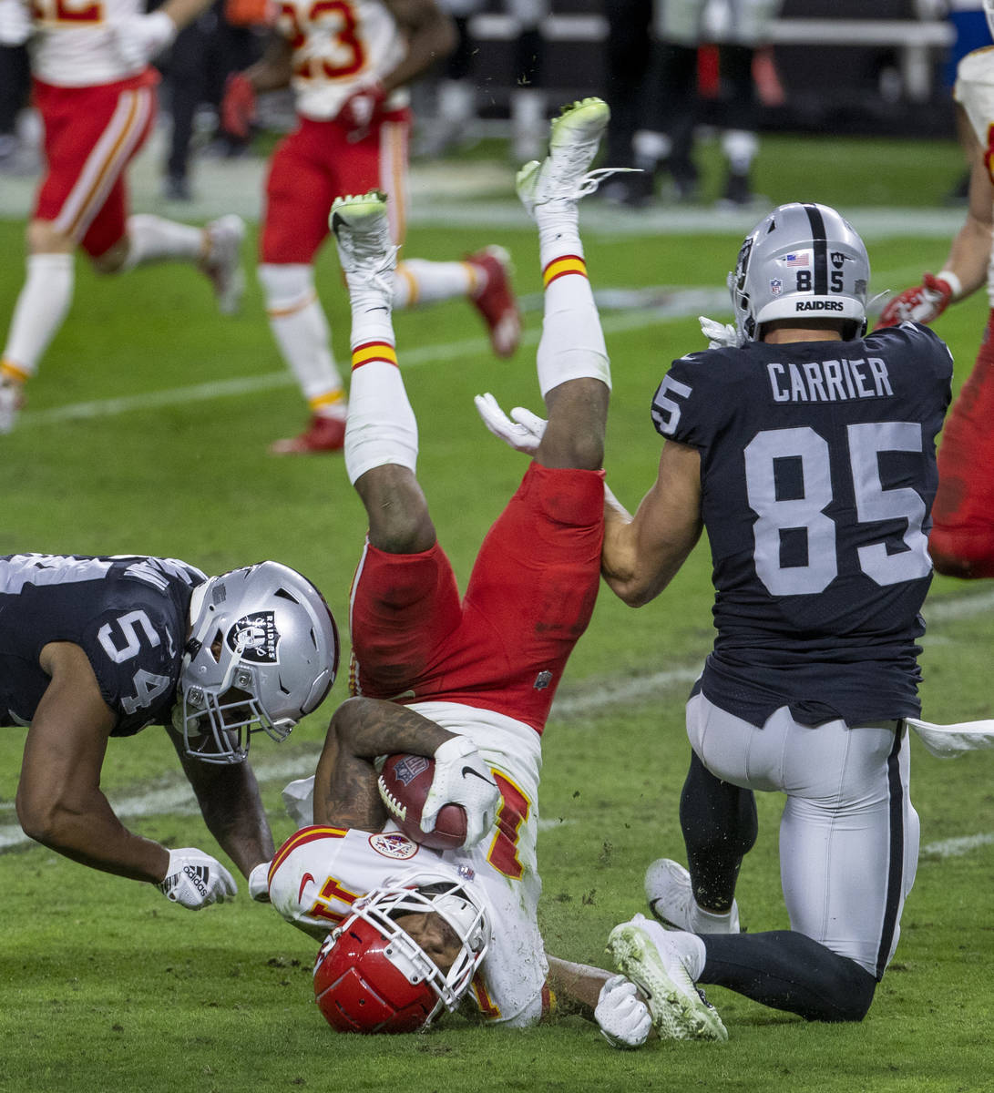 Kansas City Chiefs wide receiver Demarcus Robinson (11, center) is upended by Las Vegas Raiders ...