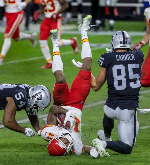 Kansas City Chiefs wide receiver Demarcus Robinson (11, center) is upended by Las Vegas Raiders ...