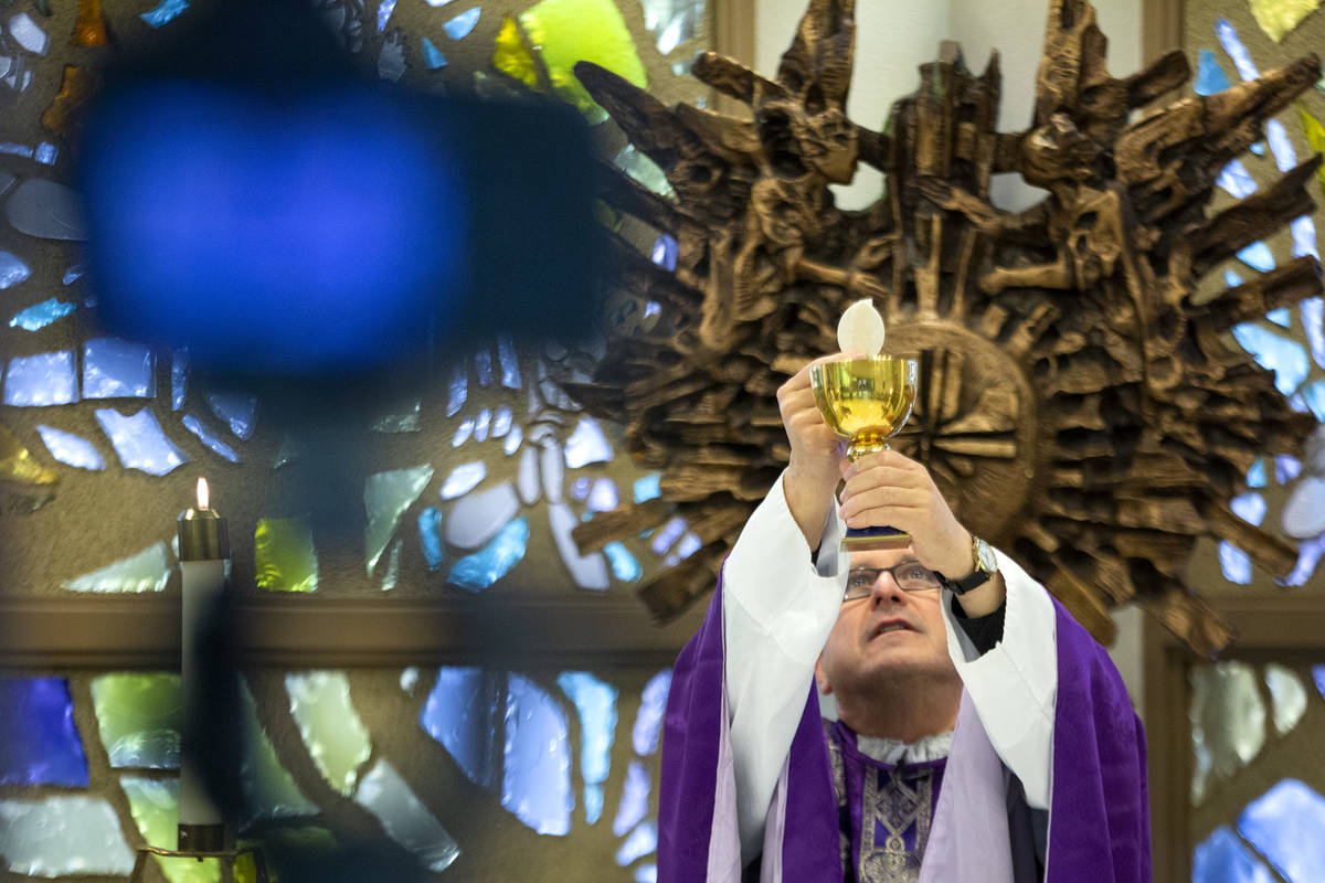 A camera records Msgr. Gregory Gordon taking Communion during a virtual Mass at the The Roman C ...