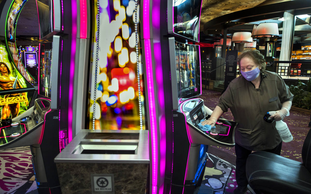 Gloria Acuna sanitizes another slot machine as guests arrive as the Mirage reopens following a ...