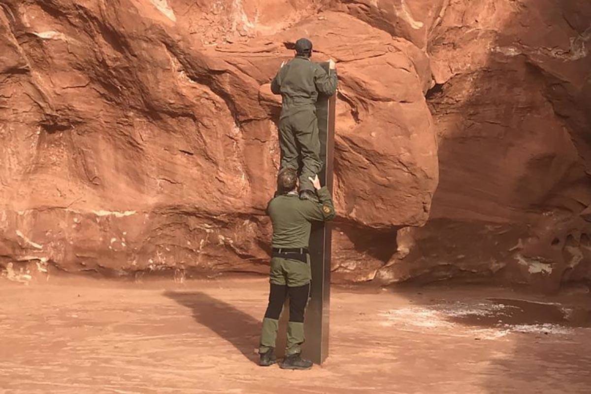 Two crew members show the height of a monolith discovered Nov. 18, 2020, in a remote southeast ...