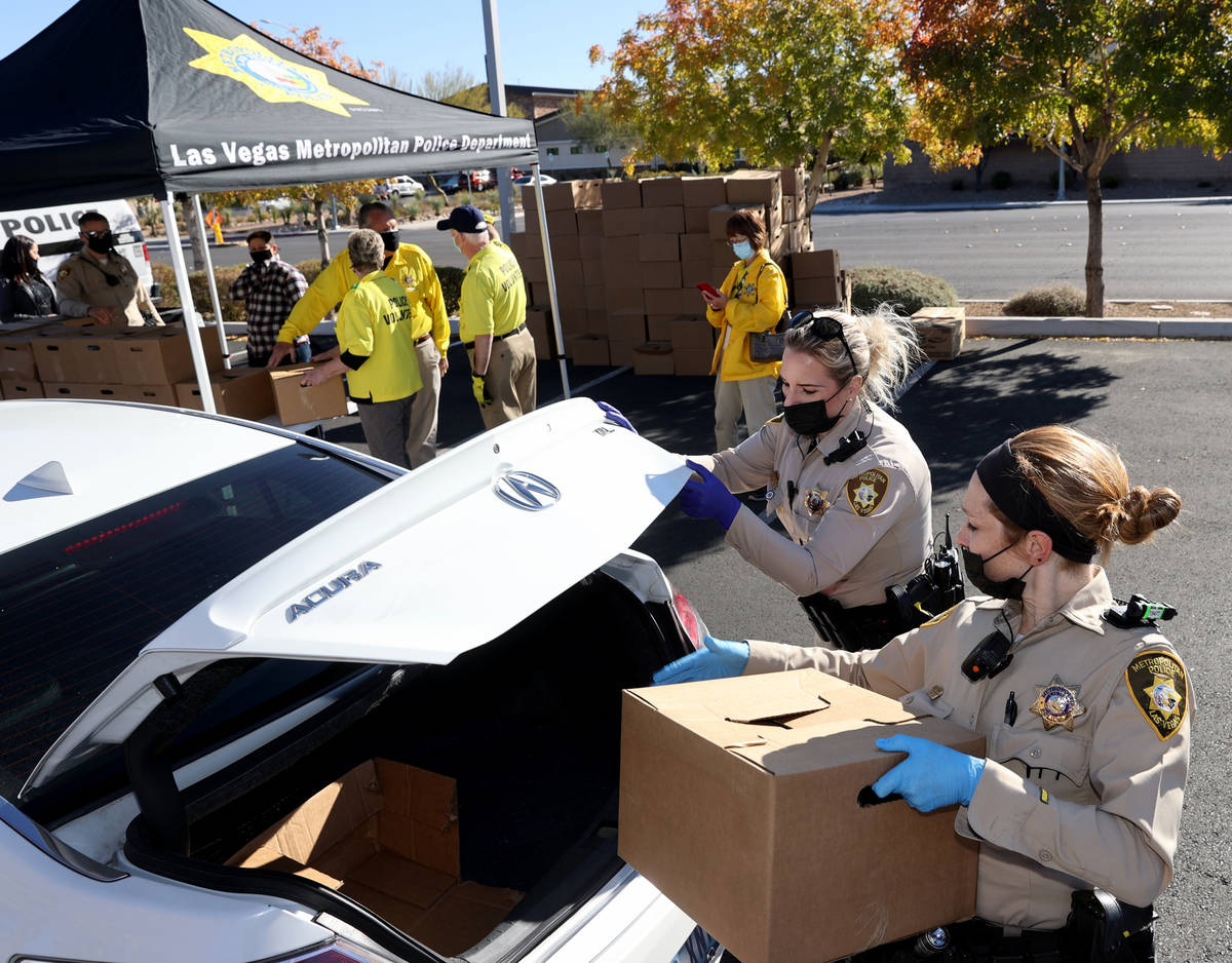 Las Vegas police officers Alyssa Karas, right, and Megan Cortez load Thanksgiving meal boxes at ...