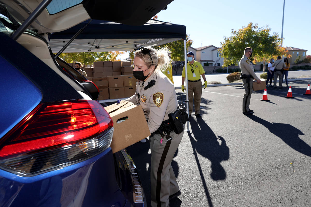 Las Vegas police officer Megan Cortez loads Thanksgiving meal boxes at Windmill Library in Las ...