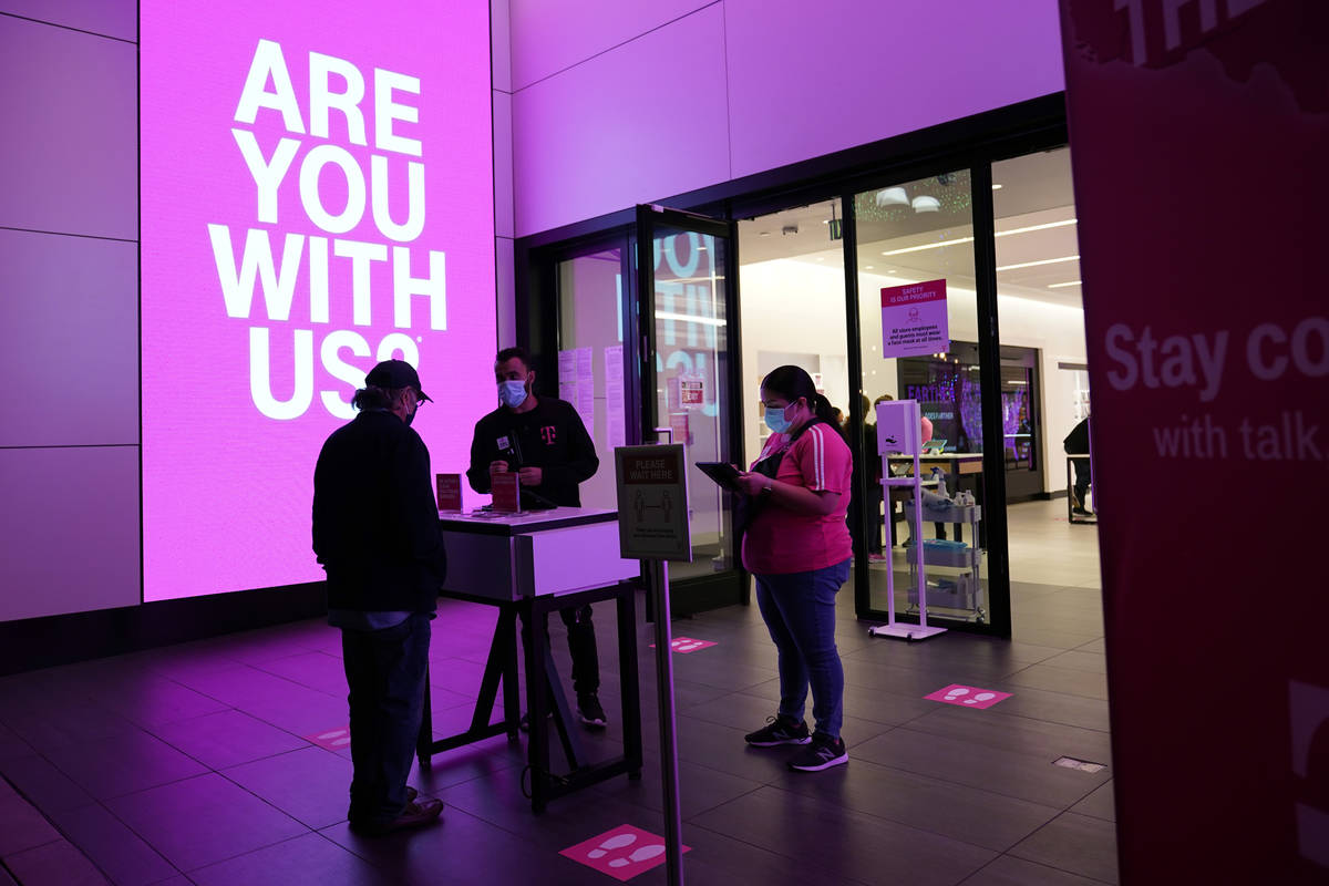 Shoppers talk to a sales person outside of a T-Mobile store Thursday, Nov. 19, 2020, in Santa M ...