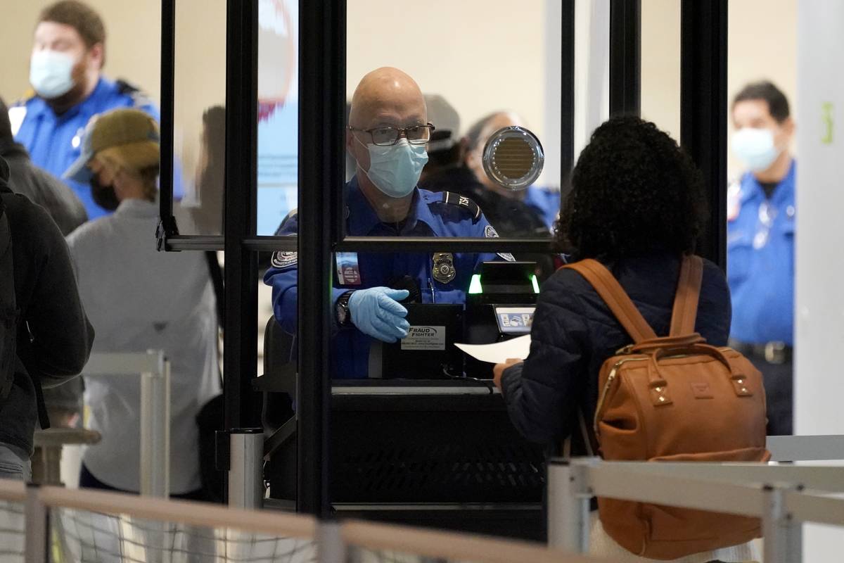 A TSA agent assist a travel at a security checkpoint at Love Field Airport in Dallas, Tuesday, ...