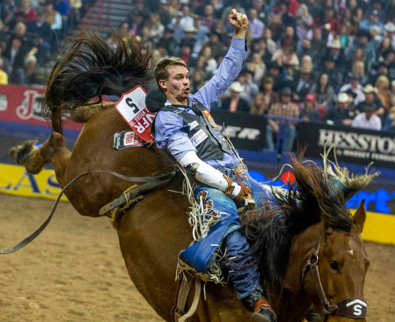 Orin Larsen of Inglis, Manitoba, digs into the saddle in Bareback Riding during the tenth go ro ...