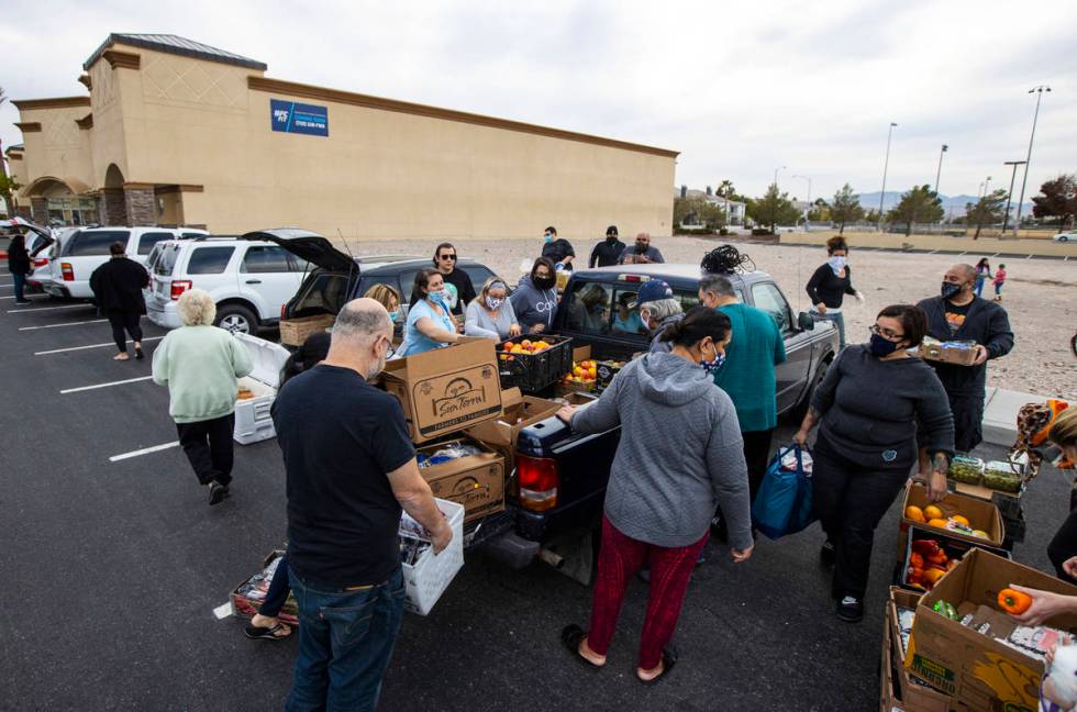 People in need get donated food from Amber Stevenson, upper right, wearing a bandana, at a shop ...