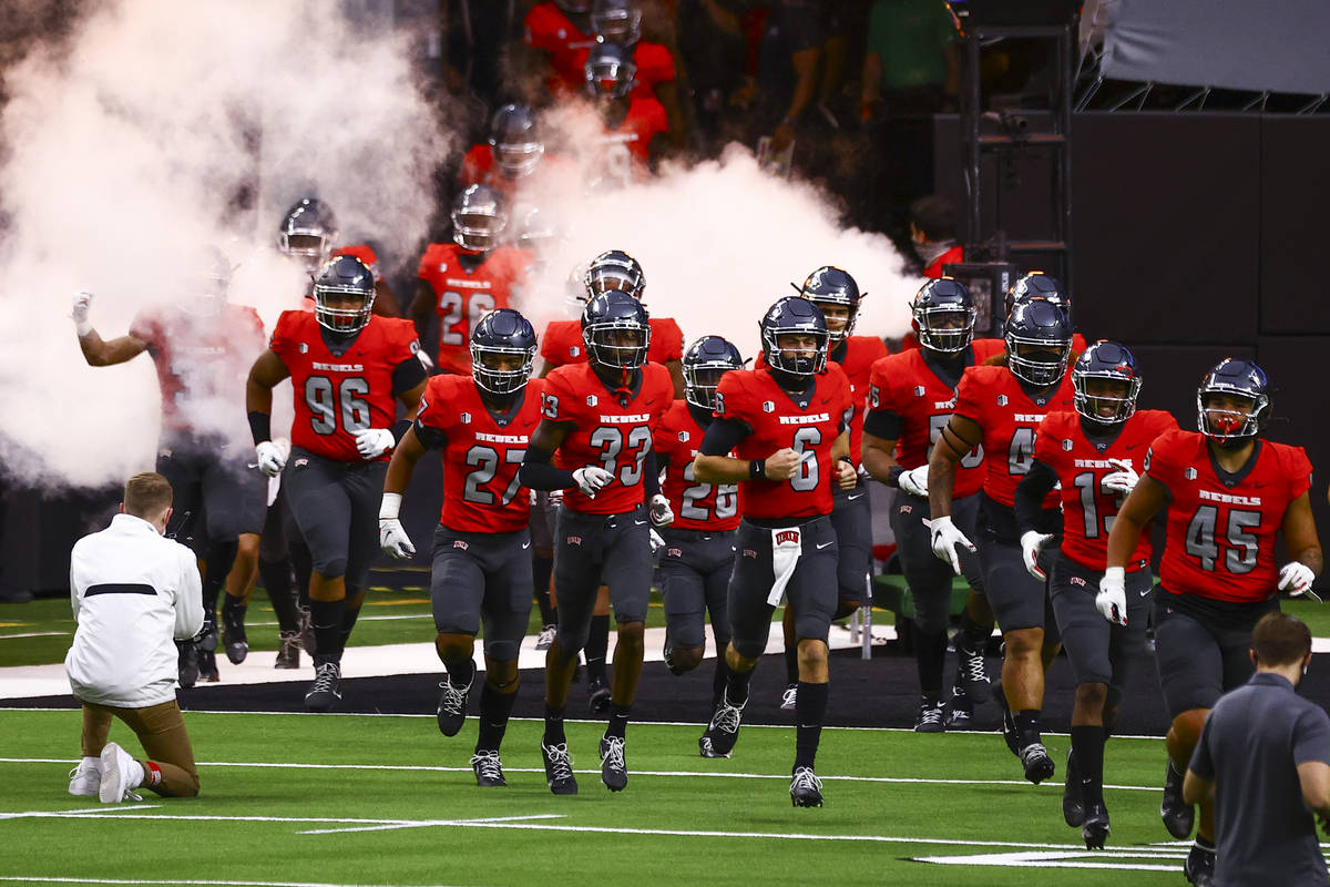 UNLV Rebels players run onto the field before taking on the Wyoming Cowboys in a football game ...