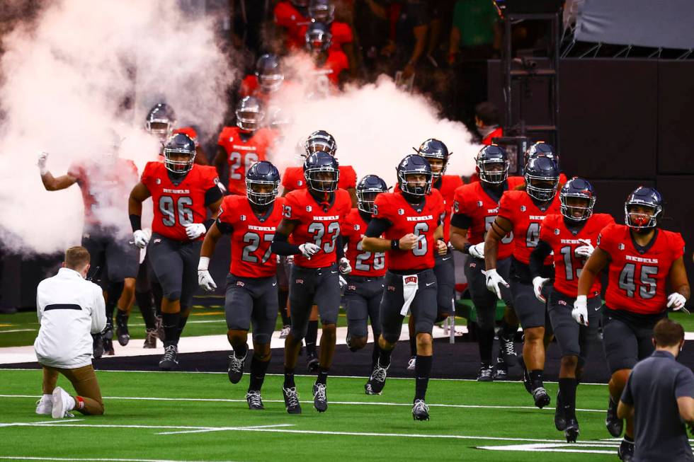 UNLV Rebels players run onto the field before taking on the Wyoming Cowboys in a football game ...