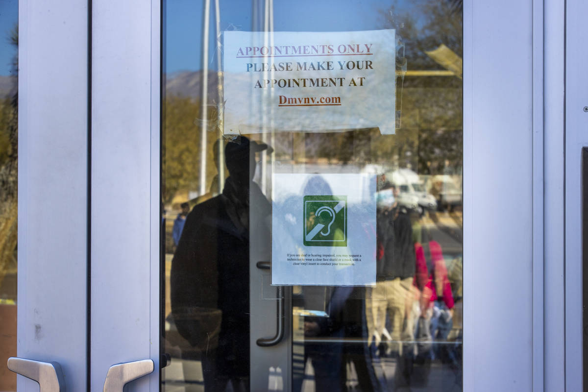 People are reflected in the front doors as long lines form regularly outside the Nevada Departm ...