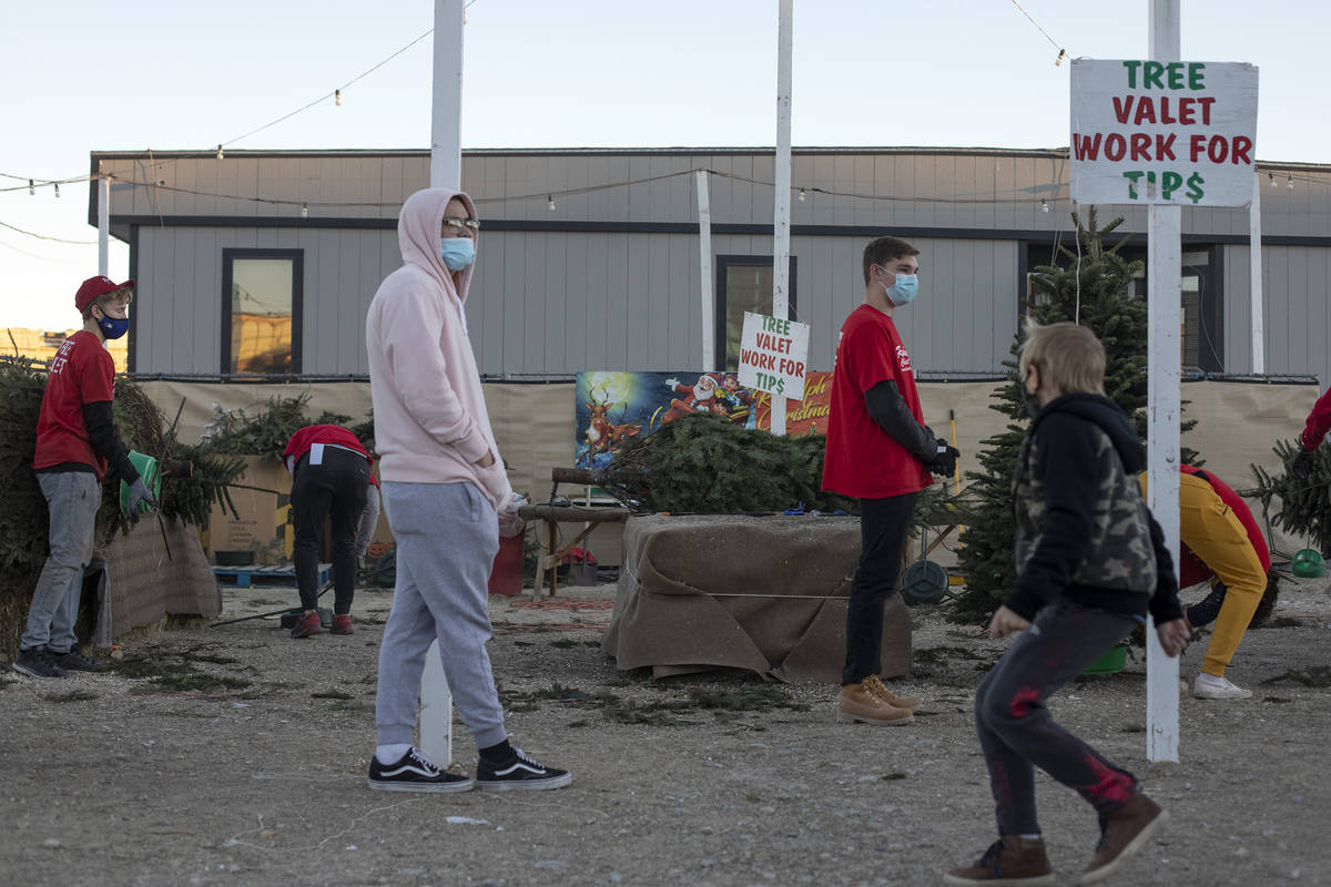 Customers wait as employees trim trees at Rudolph's Christmas Trees on Saturday, Dec. 5, 2020, ...
