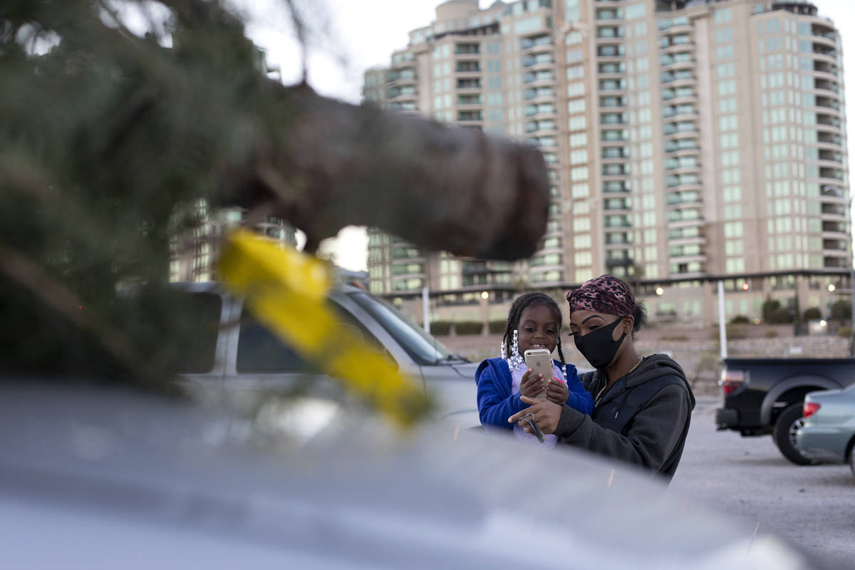 Laylay Taylor, 4, and her mom Nikki Taylor take a photo of their newly purchased tree atop thei ...