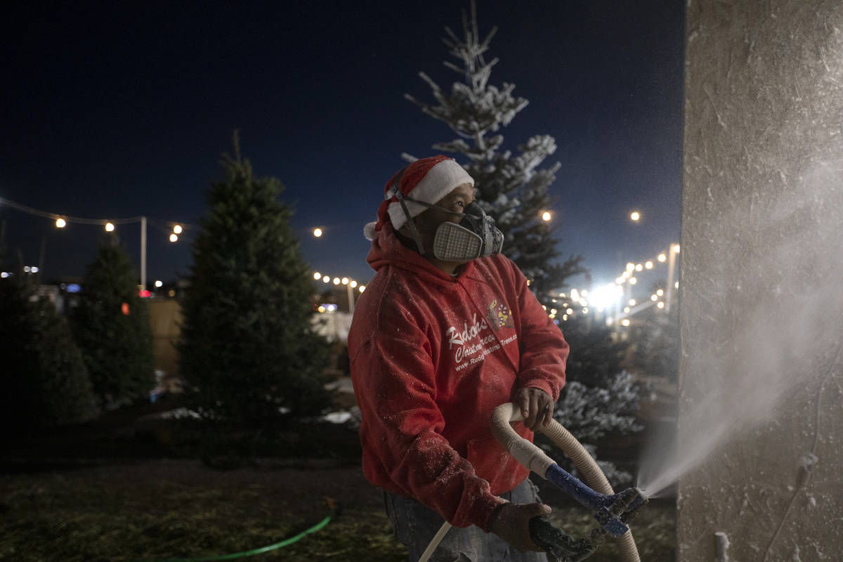 Chili Barragan sprays fake frost on a tree at Rudolph's Christmas Trees on Saturday, Dec. 5, 20 ...
