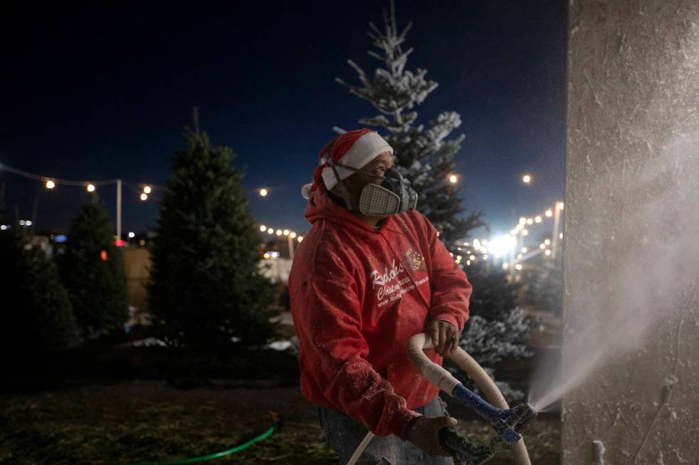 Chili Barragan sprays fake frost on a tree at Rudolph's Christmas Trees on Saturday, Dec. 5, 20 ...
