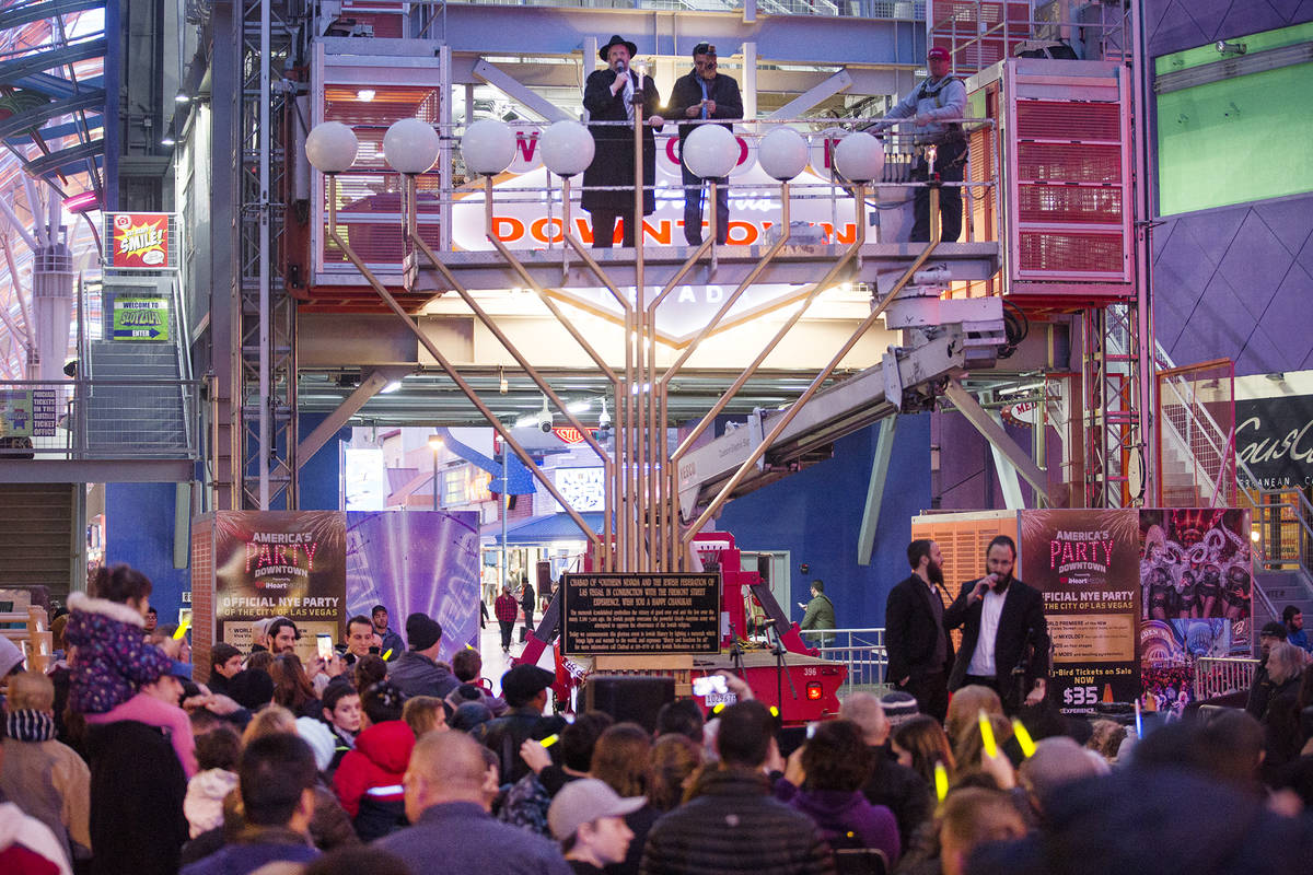 Rabbi Shea Harlig lights the menorah for the start of Hanukkah as David Dahan recites blessings ...