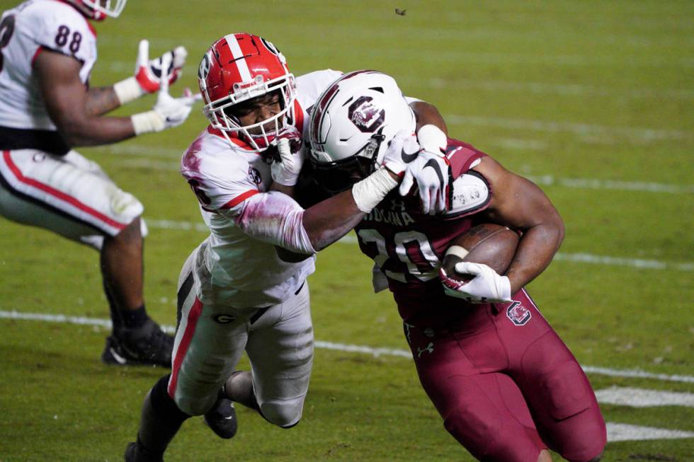 Georgia defensive back Lewis Cine (16) tackles South Carolina running back Kevin Harris (20) du ...