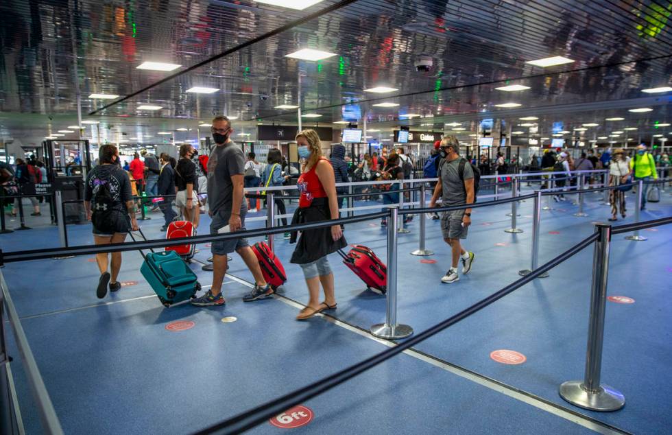 Passengers make their way through the TSA checkpoint in Terminal 1 as COVID-19 safety precautio ...