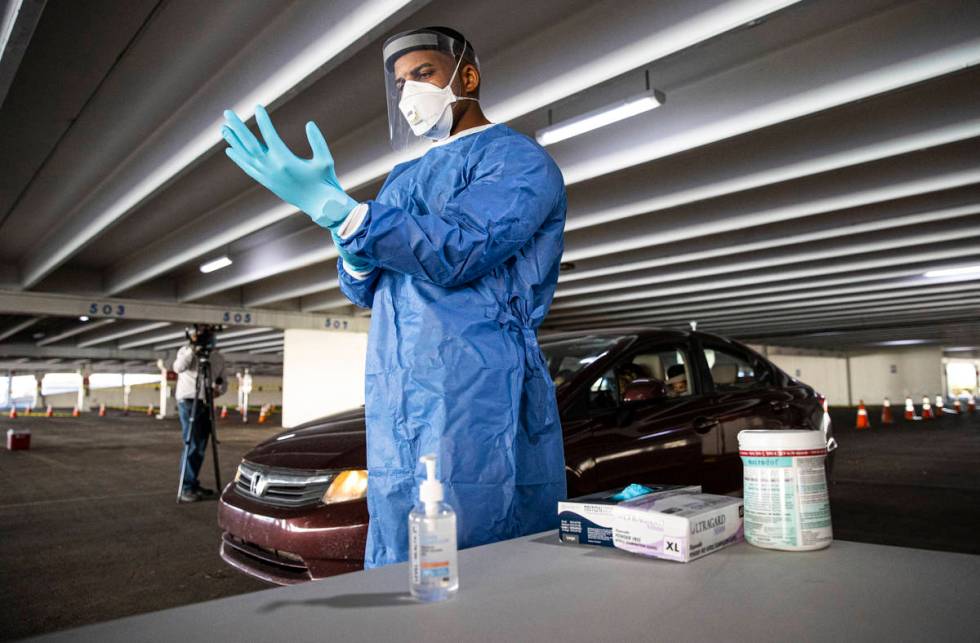 Nevada National Guard Spc. Demetrie Barnett puts on a fresh pair of gloves before taking a swab ...