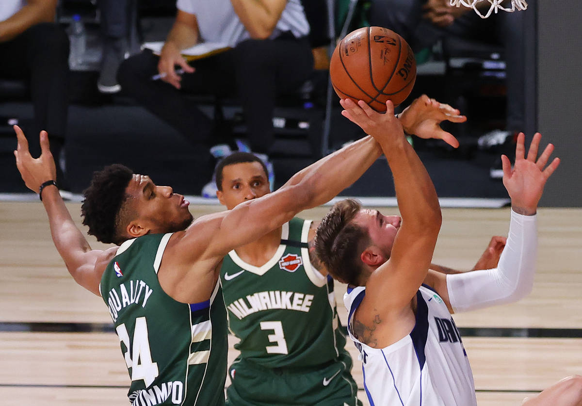 Milwaukee Bucks' Giannis Antetokounmpo (34) blocks a shot by Dallas Mavericks' Luka Doncic, rig ...