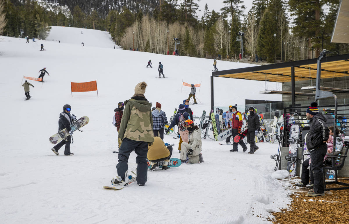 People gather about the bottom of a run near the lodge during opening day of skiing and snowboa ...