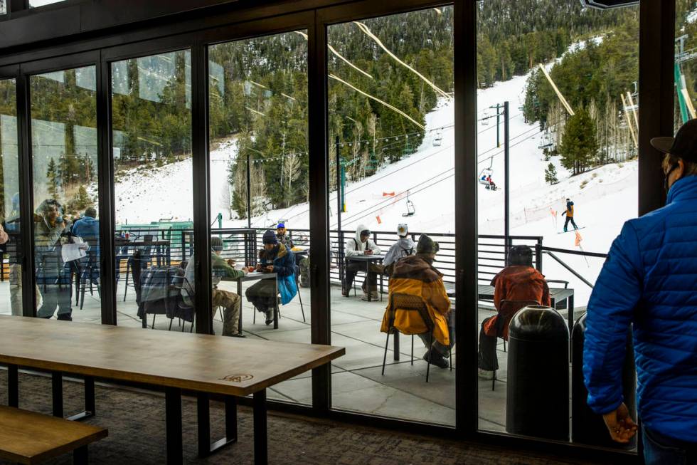People gather in the outdoor seating at the lodge during opening day of skiing and snowboarding ...