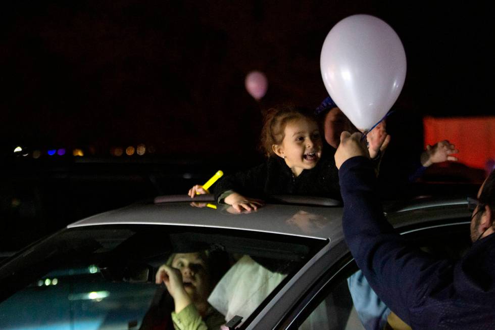 Sophie Nisgoda, 4, accepts a balloon during a drive-in Hanukkah event at the Israeli American C ...