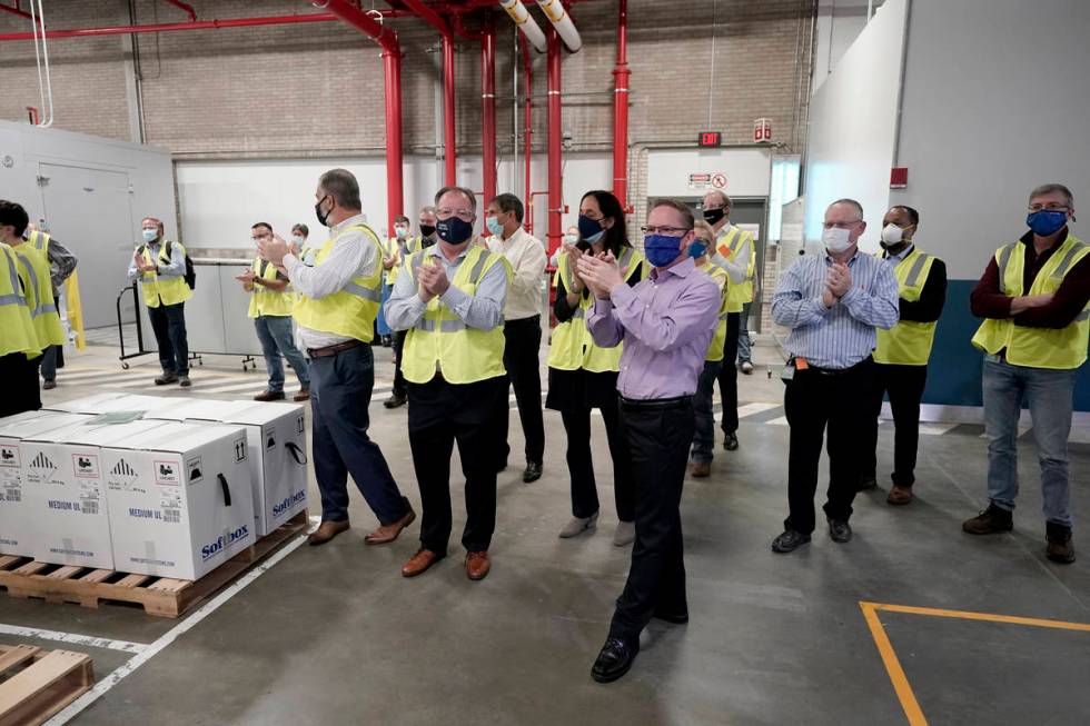 Pfizer employees clap after line workers finished packing boxes containing the Pfizer-BioNTech ...