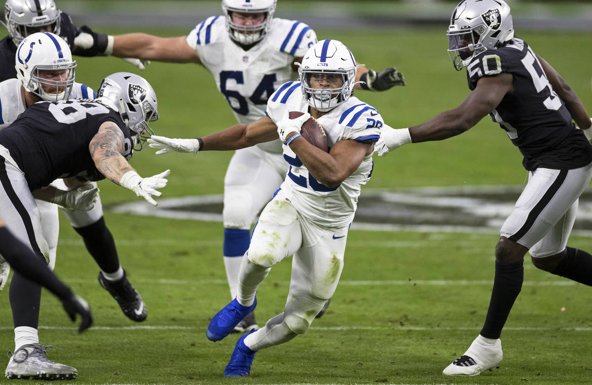 Indianapolis Colts running back Jonathan Taylor (28) bursts through a hole past Raiders defensi ...