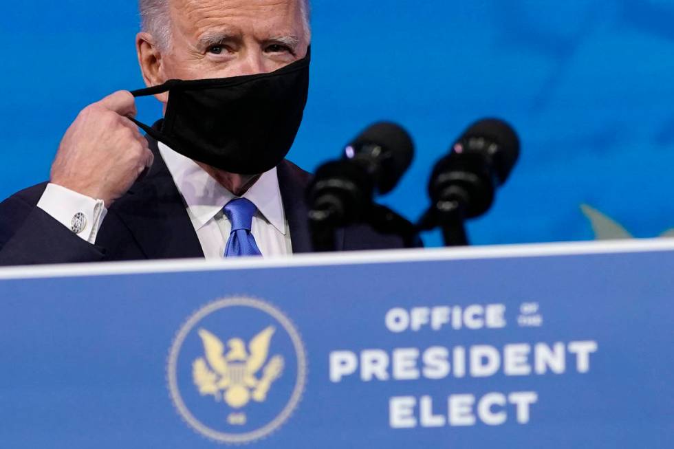 President-elect Joe Biden removes his mask as he arrives to speak after the Electoral College f ...