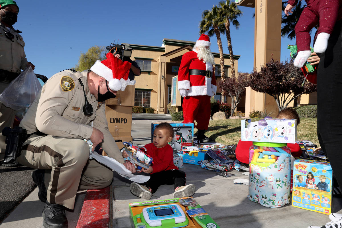 Las Vegas police officer Mike Sian watches Adriel Stephens, 1, open gifts during the Metropolit ...