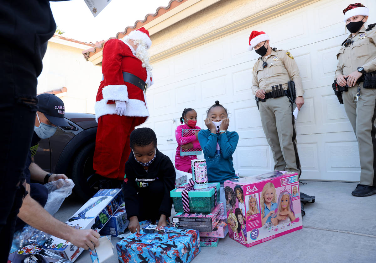 Siblings, from left, Campbell, 6 Samantha, 8, and Lela Snipes 8, open gifts during the Metropol ...