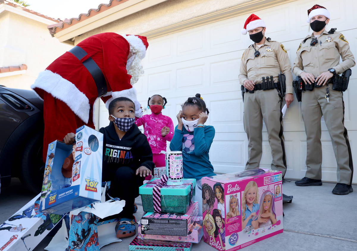Siblings, from left, Campbell, 6 Samantha, 8, and Lela Snipes 8, open gifts during the Metropol ...