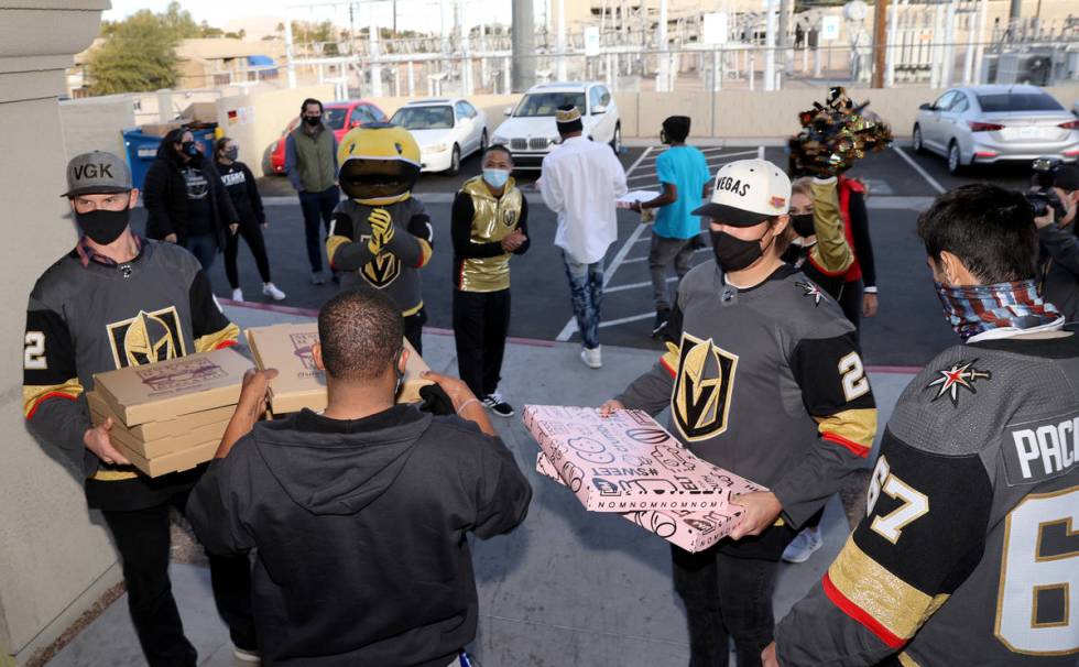 Golden Knights players, from left, Nick Holden, Zach Whitecloud and Max Pacioretty load pizzas ...