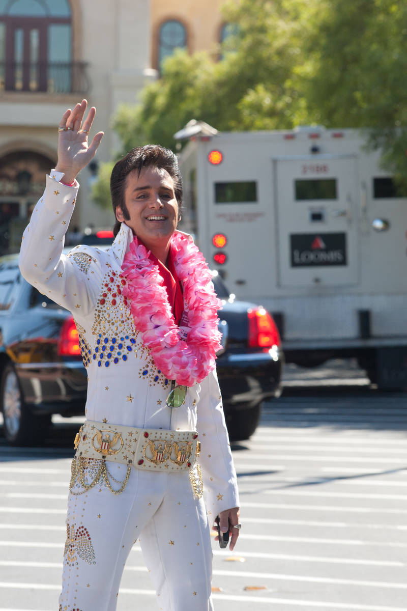 Elvis impersonator Steve Connolly flags down drivers in order to sell copies of the pink editio ...