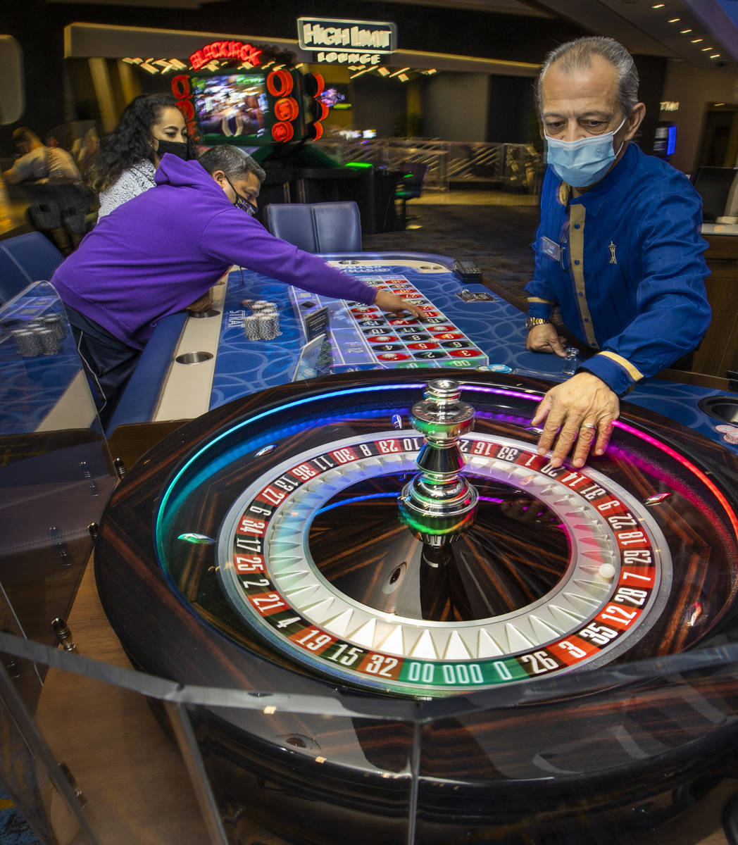 Croupier Mario Dacosta, right, fetches the ball as Marvin Alvarez, center, lays down more chips ...
