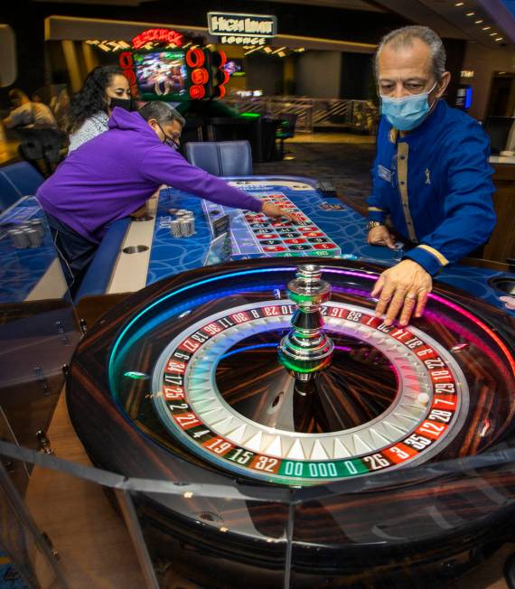 Croupier Mario Dacosta, right, fetches the ball as Marvin Alvarez, center, lays down more chips ...