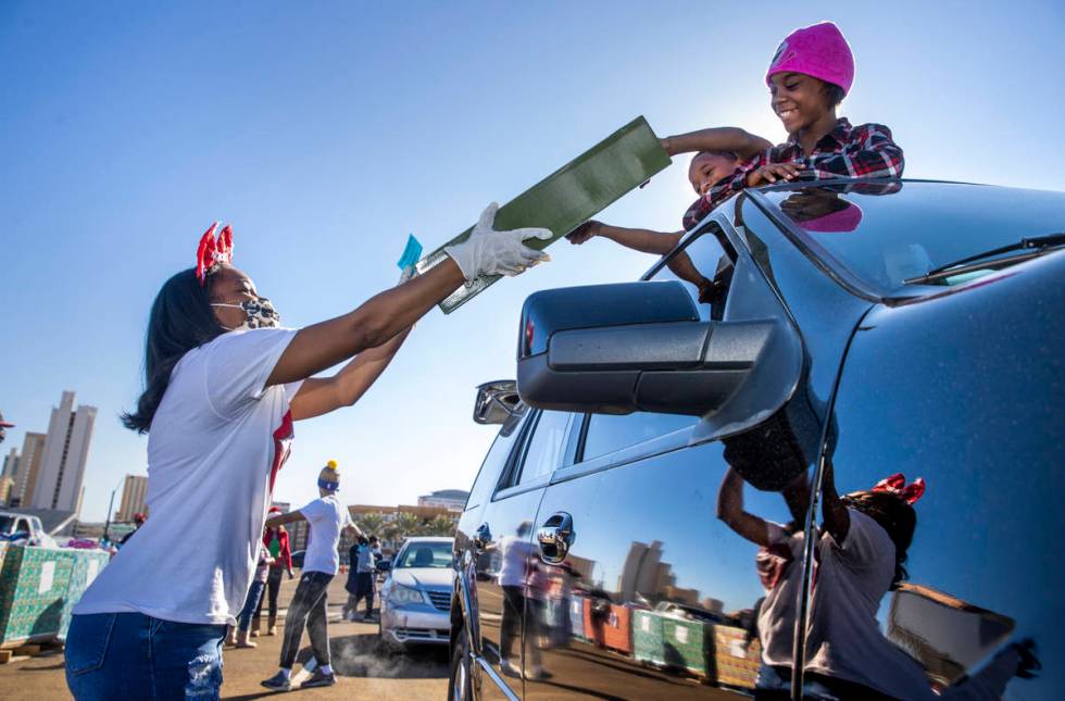 Reanna Soriano, left, hands off gifts to Jayden Murphy, 9, center, and Alicia Murphy, 10, stand ...