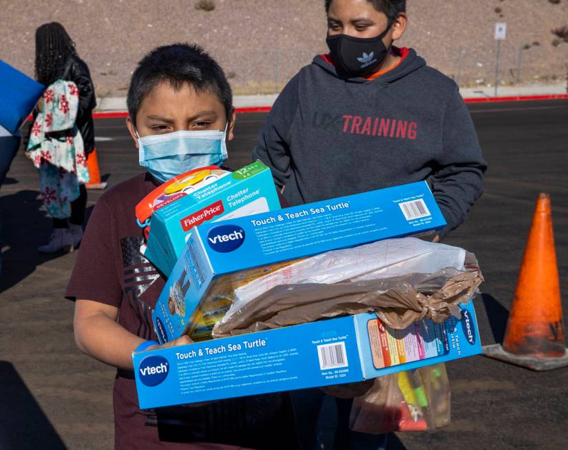 Miguel Geronimo, 8, is loaded with gifts received during the Las Vegas Rescue Mission toy drive ...