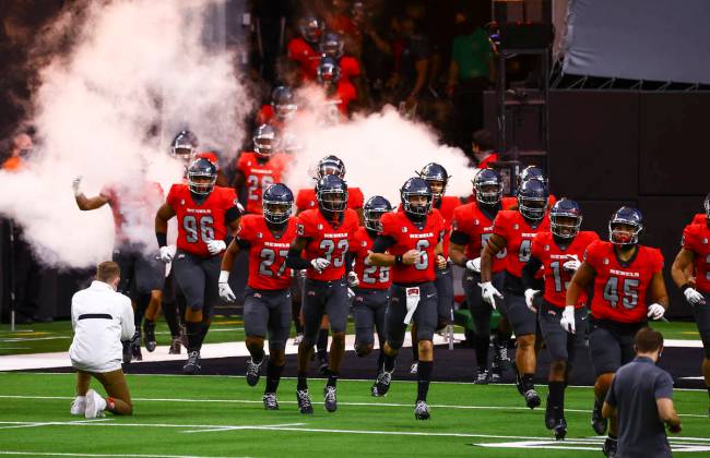 UNLV Rebels players run onto the field before taking on the Wyoming Cowboys in a football game ...