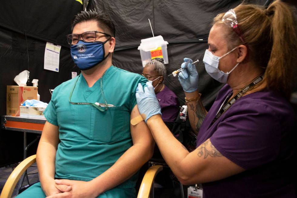 Dr. Myron Kung, left, is given the COVID-19 vaccine by nurse Darlene Roberts at the North Las V ...