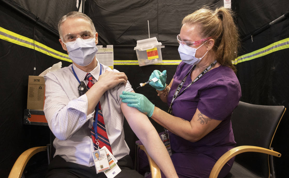 Dr. Jason Dazley, left, is given the COVID-19 vaccine by nurse Darlene Roberts at the North Las ...