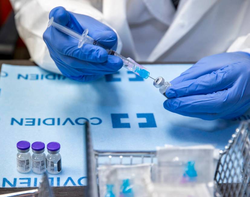 Student pharmacist Wilbur Quimba loads up new syringes with vaccine as University Medical Cente ...