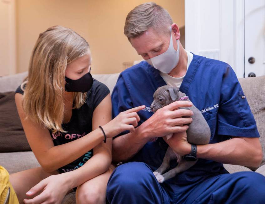Bryn, 11, left, and her dad Darrick Neibaur play with a 6-week foster puppy, through the Animal ...