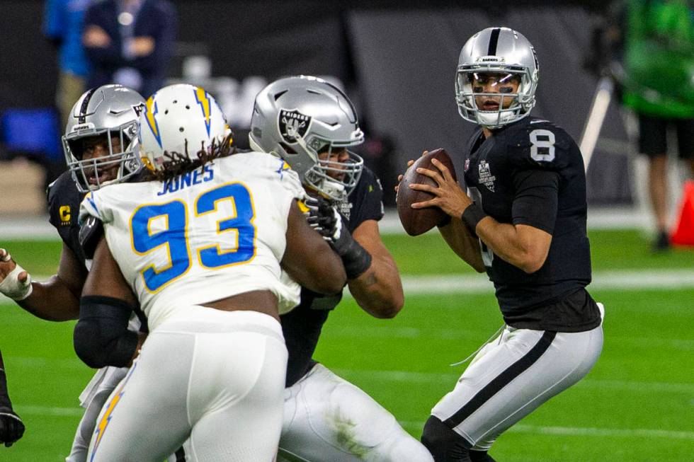 Raiders quarterback Marcus Mariota (8) drops back to pass as Los Angeles Chargers defensive tac ...