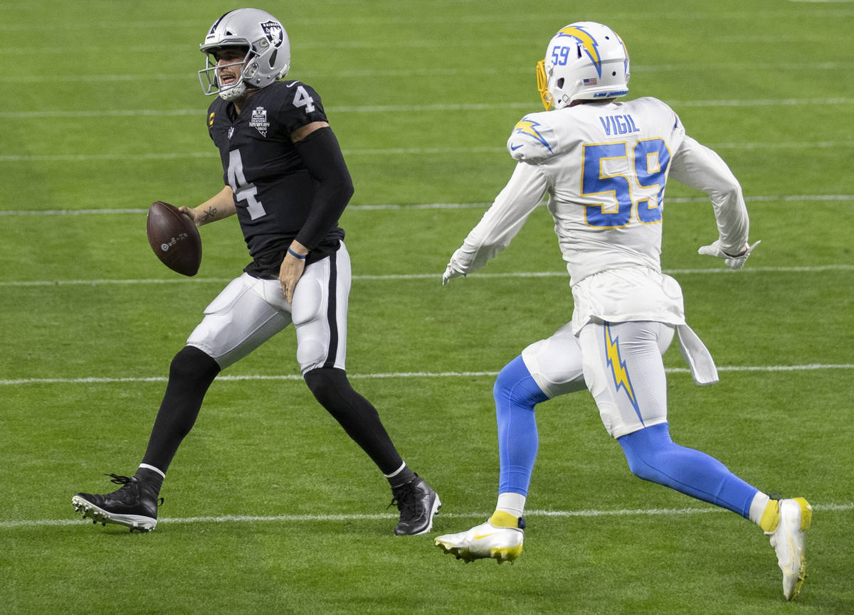 Raiders quarterback Derek Carr (4) winces in pain as he scramble towards the sideline with Los ...