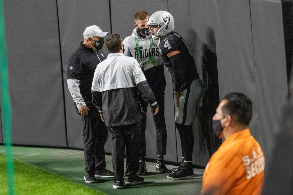 Raiders quarterback Derek Carr (4) is attended to by trainers after injuring his groin on a run ...