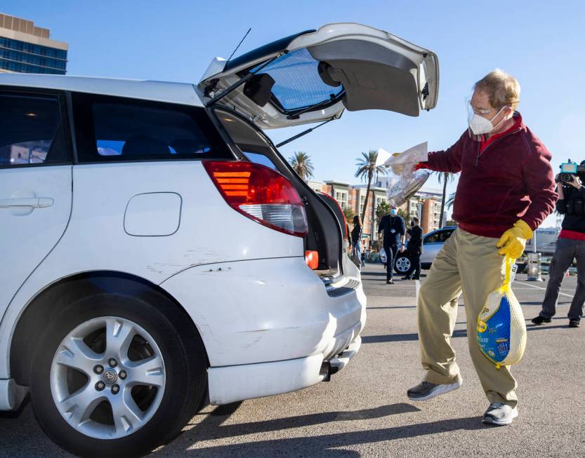 Raymond Teller delivers a turkey and cookies to an awaiting vehicle during the re-opening of th ...